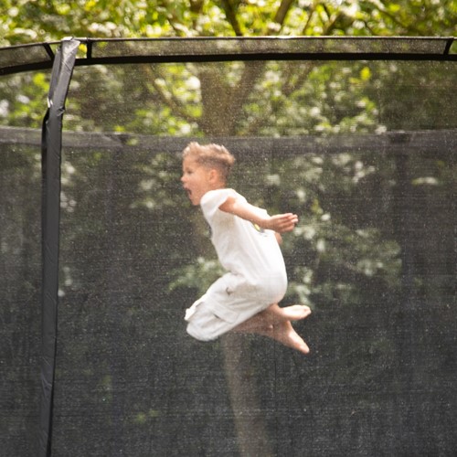 Sfeerbeeld van de VirtuFit Premium Trampoline waarbij de fijne mazen van het veiligheidsnet en de stabiele constructie tijdens het springen zichtbaar zijn.