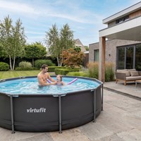 Lifestyle foto van vader en dochter spelend in het ronde VirtuFit Frame Zwembad antraciet op een modern terras.